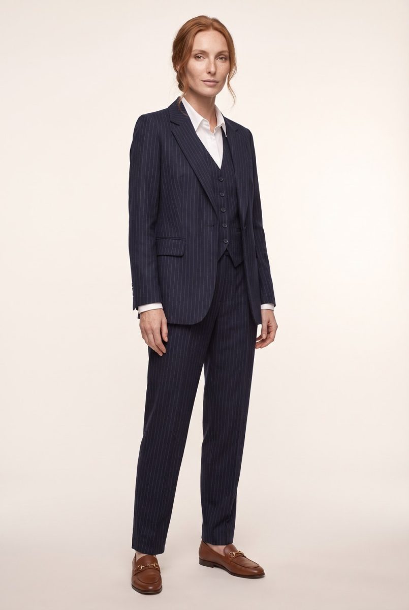 Elisabeth a figura intera in completo gessato blu notte con gilet, camicia bianca e mocassini