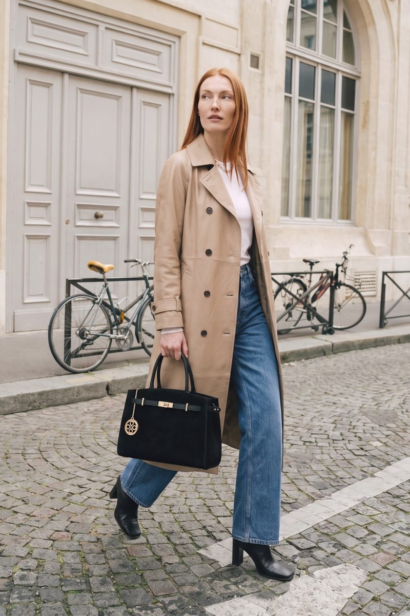 Elisabeth in trench cammello e jeans in una strada di Parigi, con le biciclette dietro